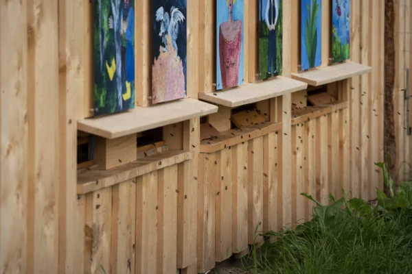 Bienen fliegen zu den kunstvoll gestalteten Eingängen eines Bienenhauses auf Gut Wulksfelde.